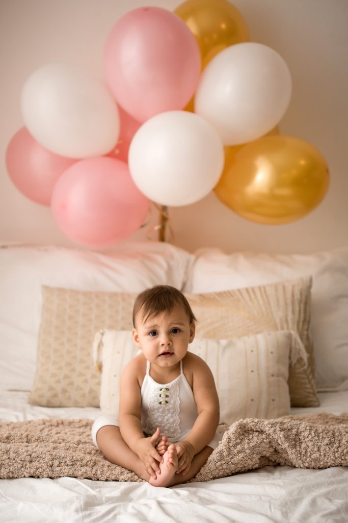 bambina di 12 mesi gioca sul letto con palloncini