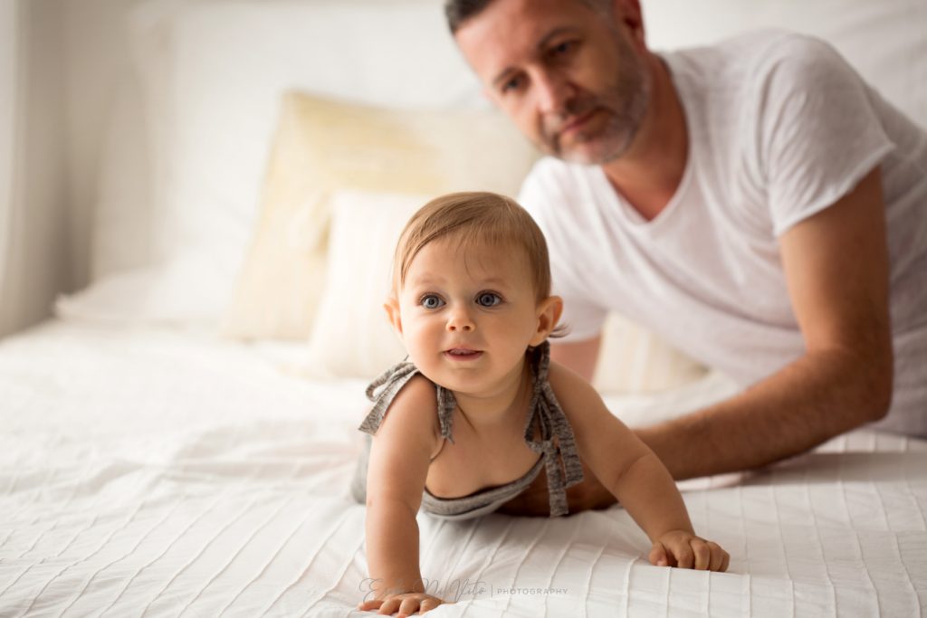 bambino 10 mesi gioca sul letto con papa